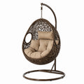 Sillón colgante de ratán sintético marrón con cojines beige y estructura de acero